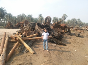 A boy standing in front of military scrap metal in Shat’l arab, an area near Basrah.