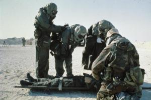 United States troops wearing NBC [Nuclear Biological and Chemical] outfits with a 'wounded' soldier on a stretcher during an exercise before the start of operations in Kuwait, 1991. 
